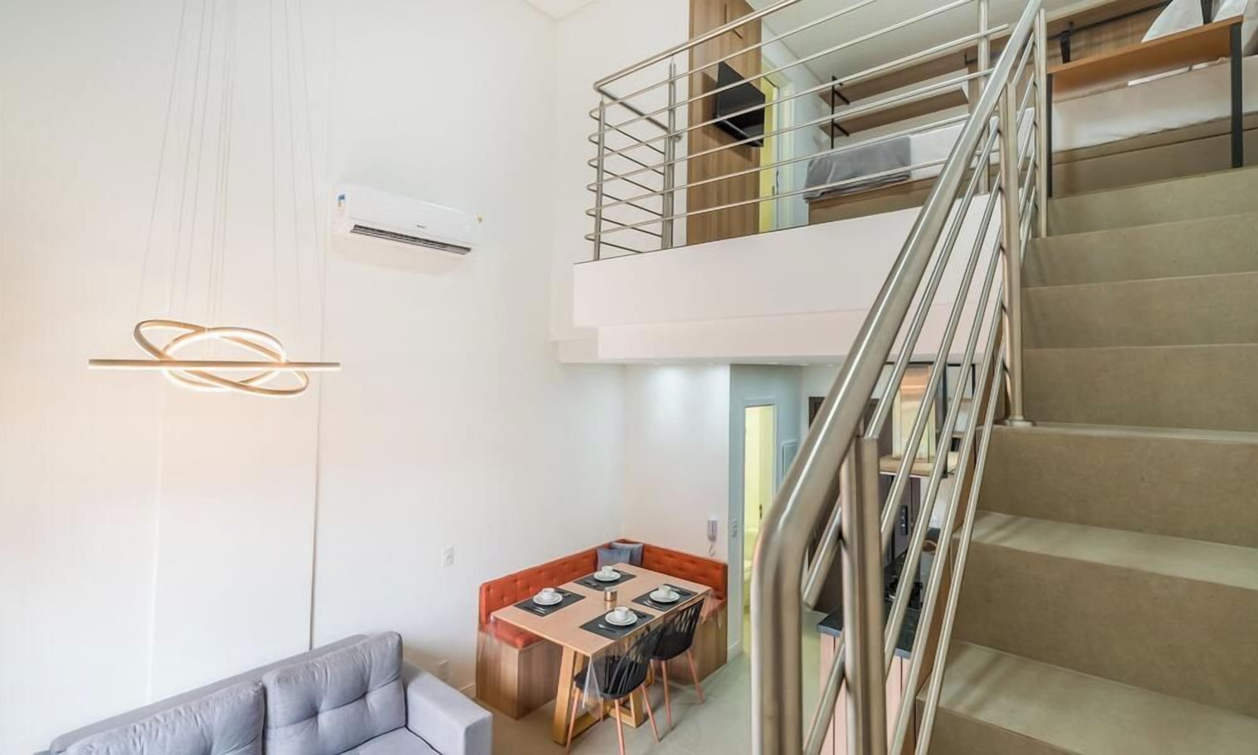 Un interior moderno con una escalera, una zona de comedor y un sofá.