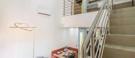 A modern interior with a staircase, a dining area, and a sofa.
