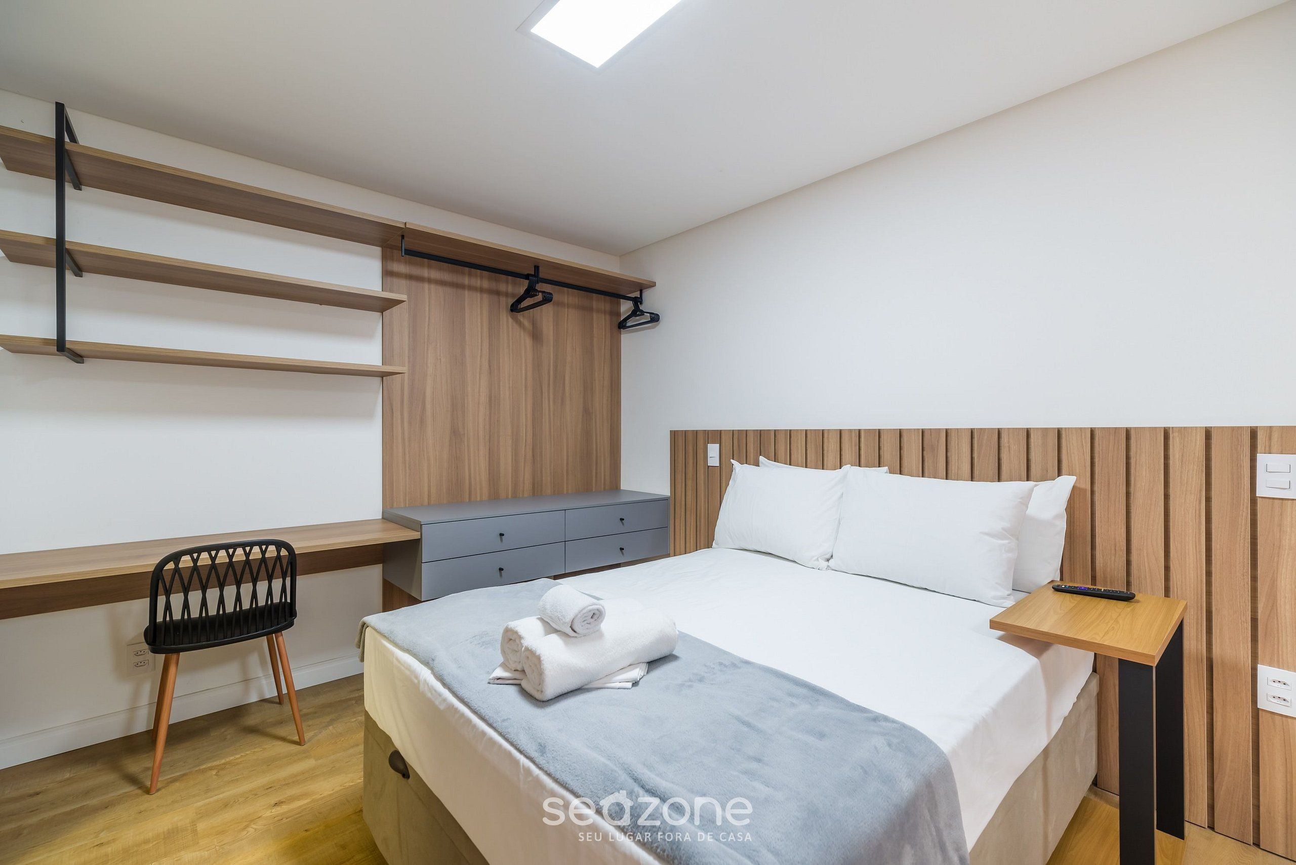 Een moderne slaapkamer met een bed, een bureau met stoel en een kledingkast.