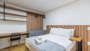 Un dormitorio moderno con una cama, un escritorio con silla y un armario.