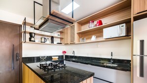 A modern kitchen with a black granite countertop, stainless steel appliances, and wooden shelves. - Apartment With Barbecue 280m From Ert0210 Beach (Florianópolis)