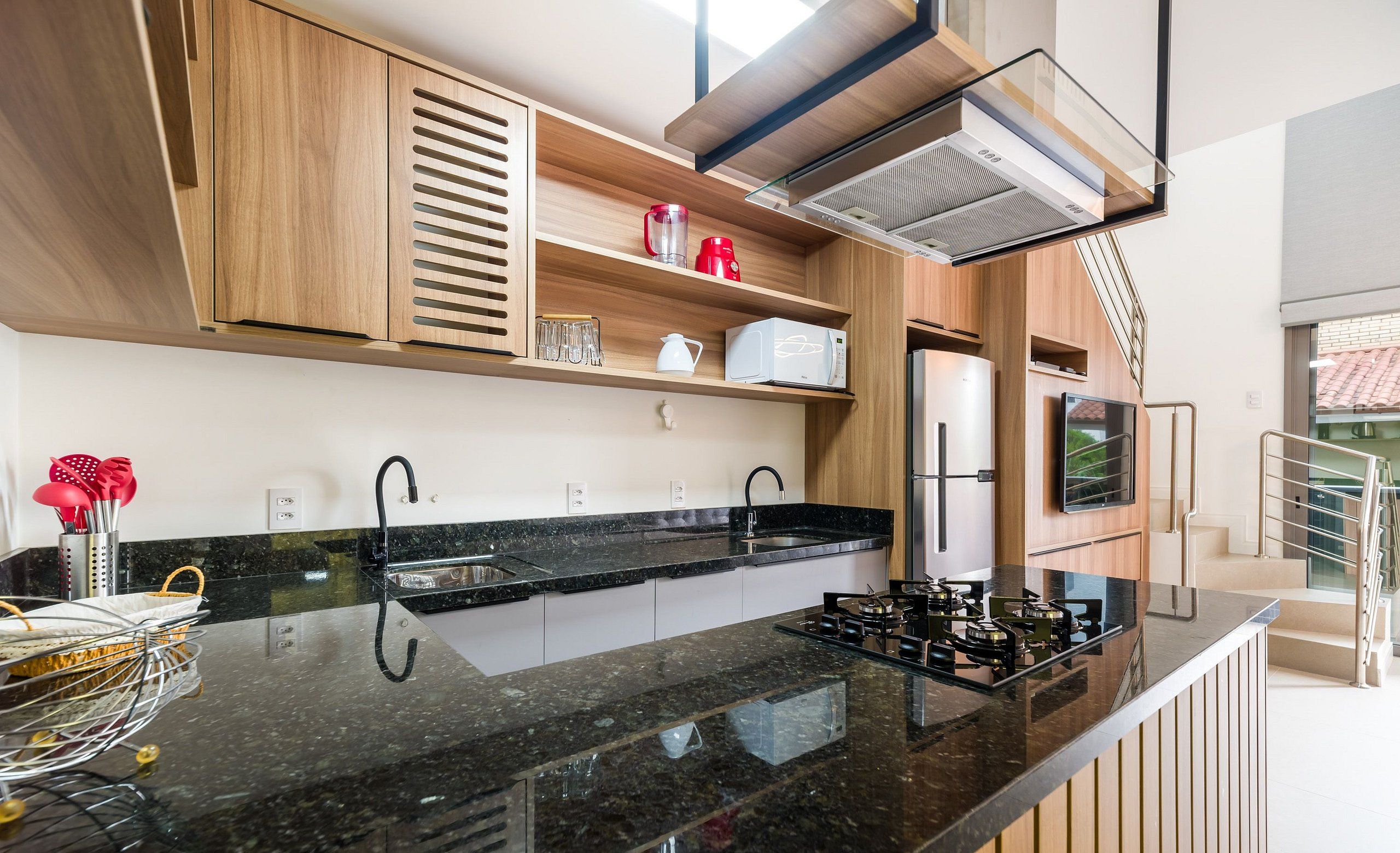 A modern kitchen with black granite countertops, wooden cabinets, and a built-in microwave.
