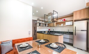 A modern kitchen with wooden cabinets, a stainless steel refrigerator, and a dining area with a table set for two. - Apartment With Barbecue 280m From Ert0210 Beach (Florianópolis)