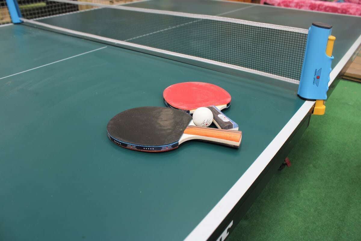 A table tennis table with two paddles and a ball.