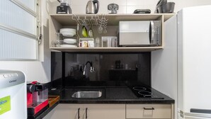Una cocina compacta equipada con cafetera, microondas y escurreplatos.