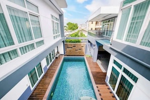 Un hotel moderno con piscina centrale, numerosi balconi e vista sugli edifici circostanti.