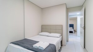 Ein modernes Hotelzimmer mit einem Einzelbett, einer grauen Decke und einem weißen Kopfkissen.