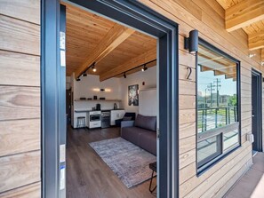 A modern interior with a wooden ceiling, a kitchen area, and a seating area with a sofa and rug.