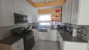 A kitchen with white cabinets, a black stove, a microwave, and a sink. - Charming 3-bedroom house in enchanting Cincinnati with AC Heat washer and dryer (Cincinnati)