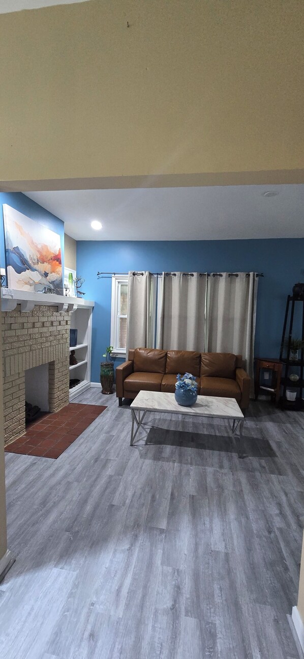 A living room with a brown leather sofa, a coffee table, a fireplace, and a blue wall.