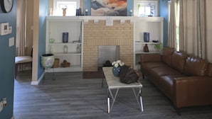 A living room with a fireplace, a sofa, a coffee table, and a clock on the wall. - Charming 3-bedroom house in enchanting Cincinnati with AC Heat washer and dryer (Cincinnati)