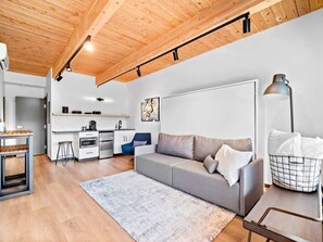 A modern living room with a grey sofa, a coffee table, and a kitchen in the background.