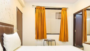 Ein Hotelzimmer mit einem Bett, einem kleinen runden Tisch und zwei mit Vorhängen versehenen Fenstern.