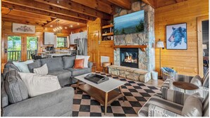 A cozy cabin interior with a fireplace, wooden walls, a checkered floor, and a sofa. - Luxury-8BR-Lodge-Game Room-Theater&MountainViews (Sevierville)