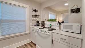 Una cocina con electrodomésticos blancos, una estación de café y un cartel que dice 'Coffee'.