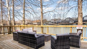 A wooden deck with wicker furniture and a warning sign. - Tranquil 3-bedroom house with dock in Kemah (Kemah)