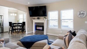 A living room with a fireplace, a flat-screen TV, and a couch. - Tranquil 3-bedroom house with dock in Kemah (Kemah)