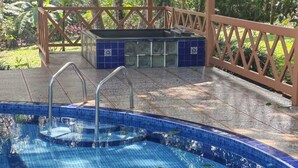 A swimming pool with a tiled deck and a covered area with a pergola. - Villa Azul  (Quesada)