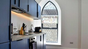 A modern kitchen with dark cabinetry, a built-in oven, and a window with a decorative glass pattern.