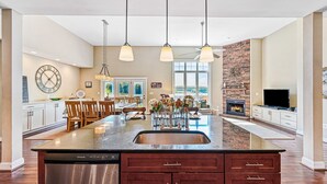 A spacious kitchen with a central island, pendant lighting, and a stone accent wall.