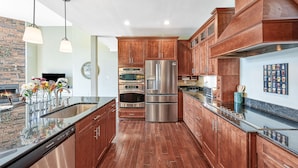 A modern kitchen with wooden cabinets, stainless steel appliances, and a granite countertop.