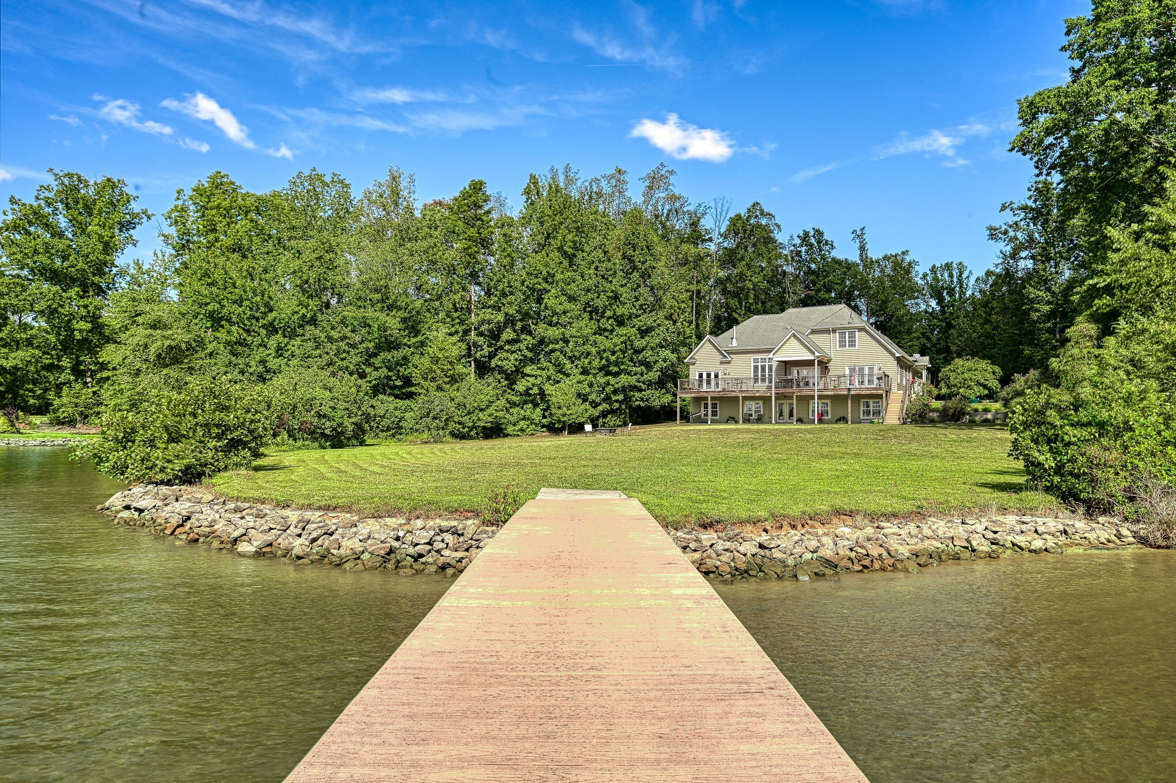 Una casa con un muelle que da a un lago, rodeada de árboles.