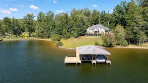 A lakeside house with a dock and a covered boat launch area.