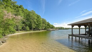 A lakeside view with a wooden pier and a covered seating area.