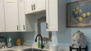A kitchen with white cabinets, a marble countertop, a sink, and a decorative vase.
