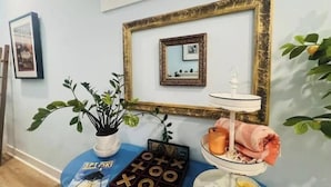 A room with a blue table featuring a board game, a small potted plant, and a framed picture on the wall.
