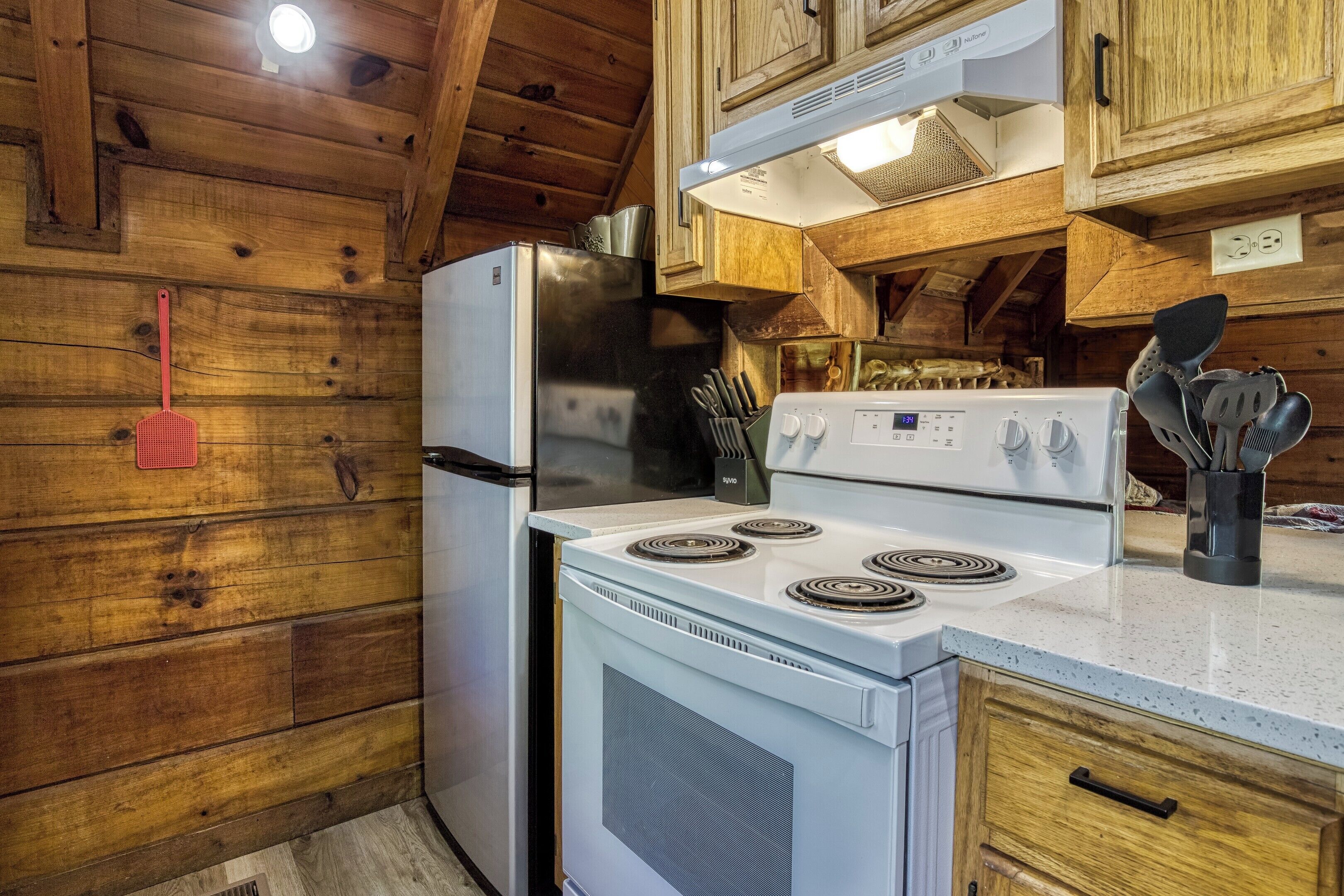A kitchen with wooden walls, a refrigerator, a stove, and a sink.