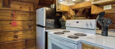 A kitchen with wooden walls, a refrigerator, a stove, and a sink.