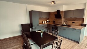 Una cocina moderna con gabinetes grises, encimera de madera y horno empotrado.