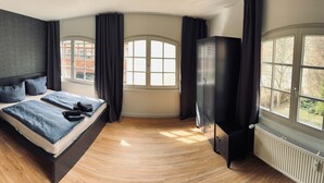 Un dormitorio moderno con cama, armario y ventanas amplias.