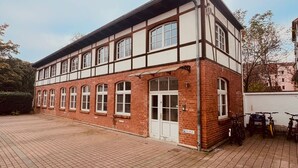 Un edificio de dos pisos con fachada de ladrillo y ventanas enmarcadas en blanco.