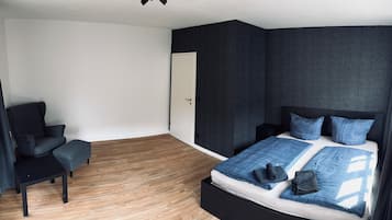 Un dormitorio moderno con cama, una silla y una mesita.