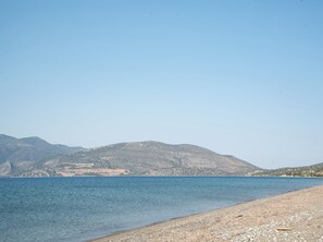 A beach with a clear view of the sea and distant mountains.