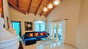 A spacious living area with a blue sofa, a glass coffee table, and a large white vase.