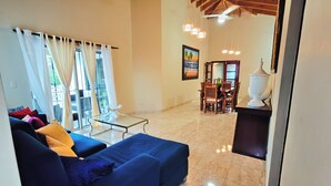 A living room with a blue sofa, dining table, chairs, and a ceiling fan.