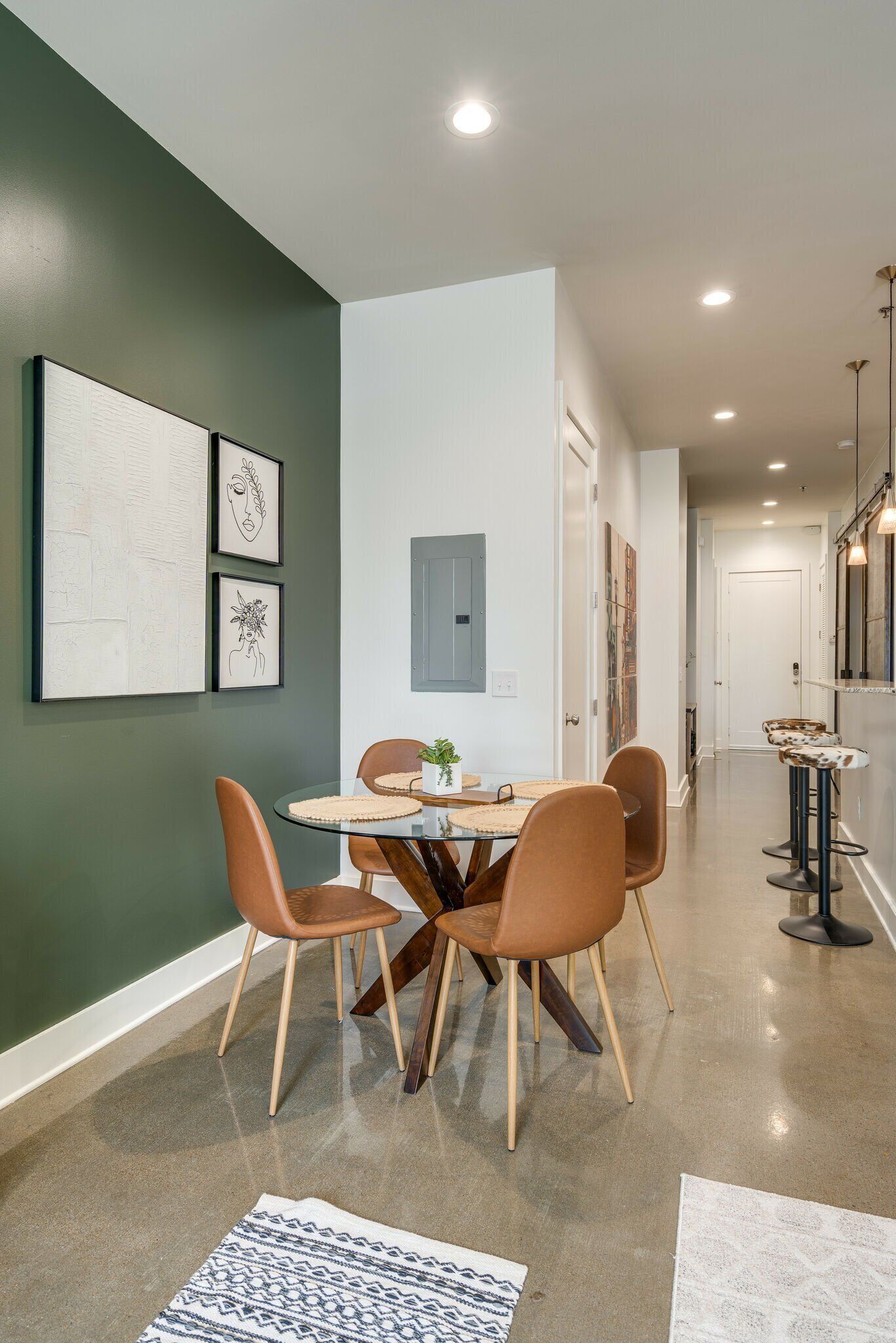 A dining area with a round table, four chairs, and artwork on the wall.
