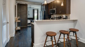 Una cocina moderna con armarios de madera oscura, electrodomésticos de acero inoxidable y una barra con taburetes.