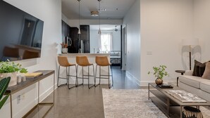 Una cocina moderna con taburetes de bar, un área de comedor con sofá y una sala de estar con mesa de centro.