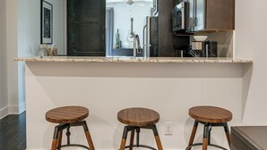 Una cocina moderna con tres taburetes de madera, una encimera e iluminación colgante.