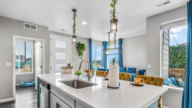 A modern kitchen with a large island, white cabinetry, and blue accents. - Entertainment Oasis 4BR w/ Home Theater & Game Room (Commerce City)