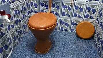 Un baño con inodoro, bidé y un balde.