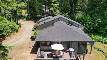 Una cabaña con terraza, rodeada de un bosque denso.