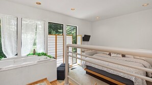 Ein Schlafzimmer mit Etagenbett, kleinem Schreibtisch, einem Fenster mit durchsichtigen Vorhängen und Blick ins Grüne.