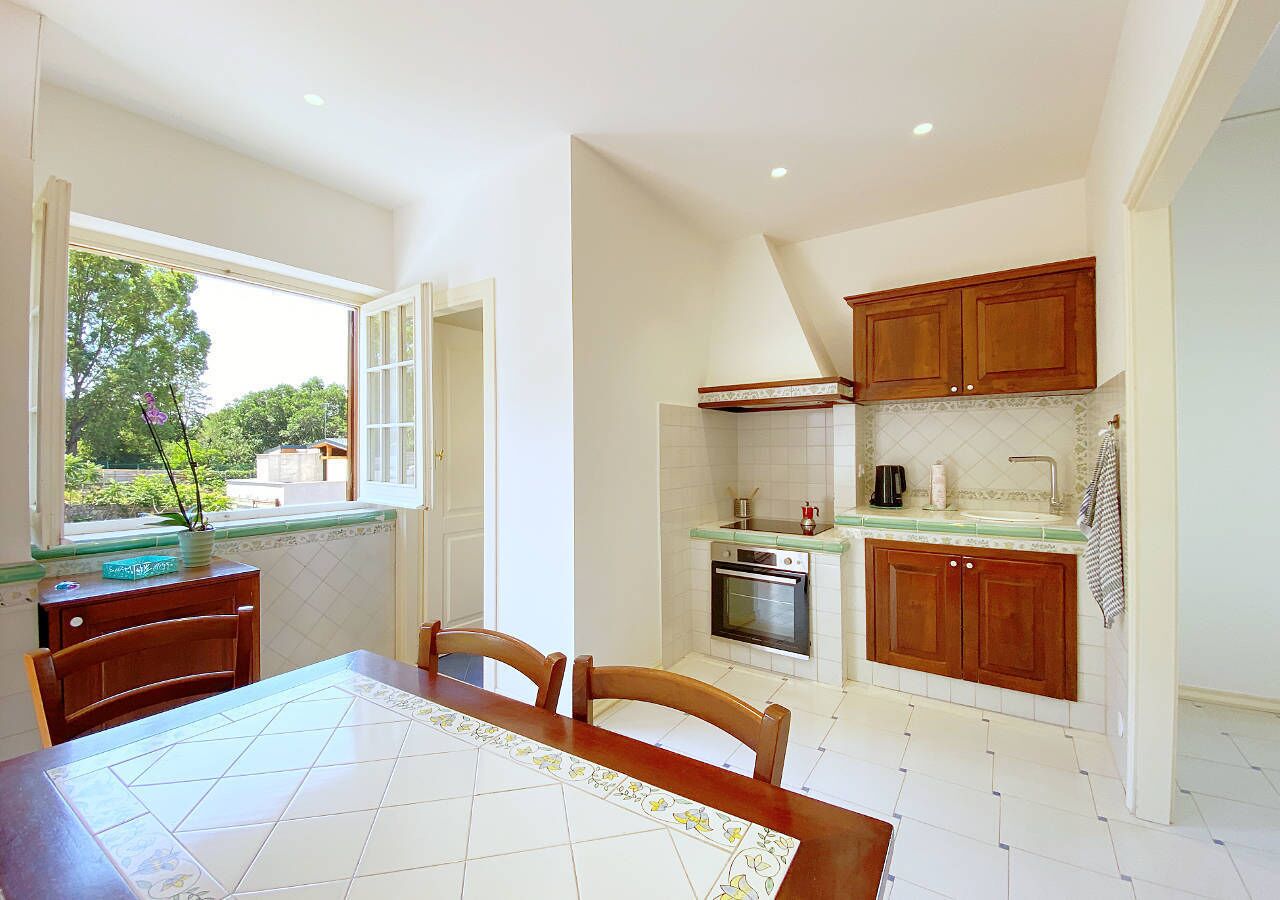 A compact kitchen with wooden cabinets, a built-in oven, and a window with a view of greenery.