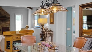A dining area with a glass-top table, two chairs, and a decorative tray with glassware.