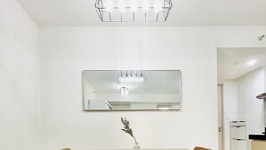 A dining area with a wooden table and chairs, a vase with a plant, and a modern chandelier.